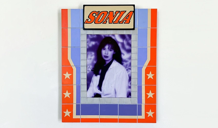photo of a flat sculpture featuring a monochrome blue and purple portrait in the center surrounded by orange titles and the word Sonia at the top